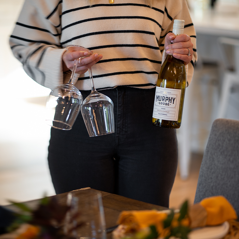 A person pouring Murphy Goode Sauvignon Blanc into a tin wine cup with Murphy Goode logo printed on the cup. 